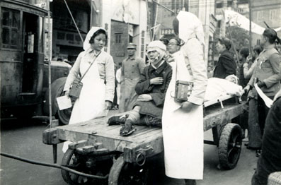 The wounded being taken to hospital on a cart, and attended by two Nurses, c.1938. Canton. Image from http://www.presbyterian.org.nz.